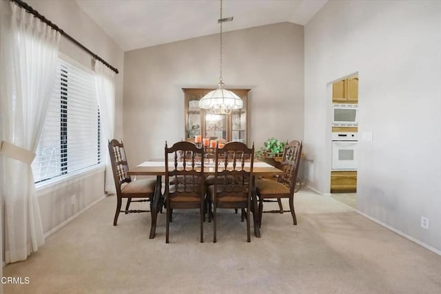 dining area with a chandelier, high vaulted ceiling, light carpet, and visible vents