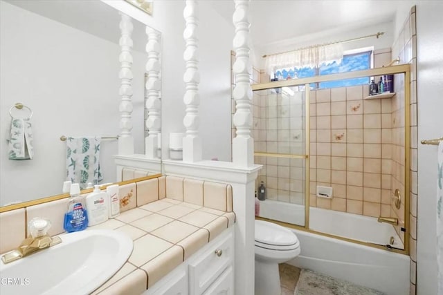 full bathroom with enclosed tub / shower combo, vanity, and toilet