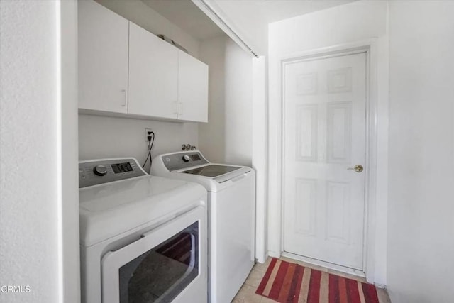 washroom featuring washing machine and dryer, cabinet space, and light tile patterned floors