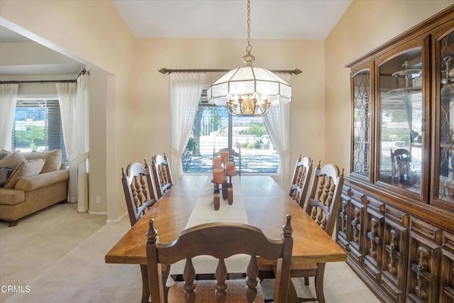 dining area with light colored carpet, a healthy amount of sunlight, and an inviting chandelier