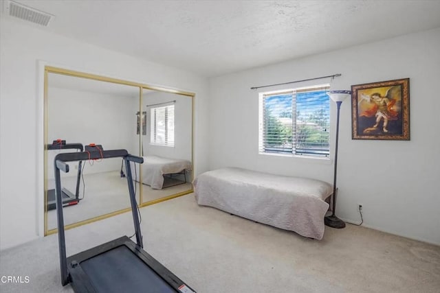 bedroom with a closet, multiple windows, visible vents, and carpet flooring