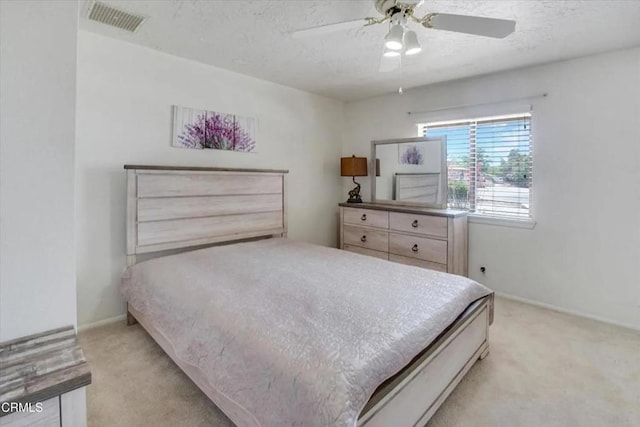 bedroom with baseboards, light carpet, visible vents, and a textured ceiling