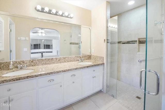 full bath featuring double vanity, a shower stall, a sink, and tile patterned floors