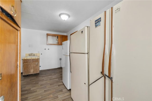 kitchen with tile counters, wood finished floors, and freestanding refrigerator