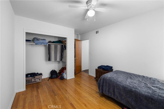 bedroom featuring a closet, visible vents, ceiling fan, wood finished floors, and baseboards