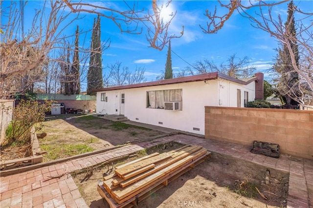 back of property with crawl space, fence, and stucco siding