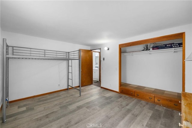 unfurnished bedroom with a closet, wood finished floors, and baseboards