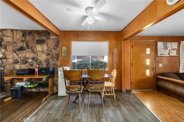 dining area featuring wooden walls, a ceiling fan, and wood finished floors