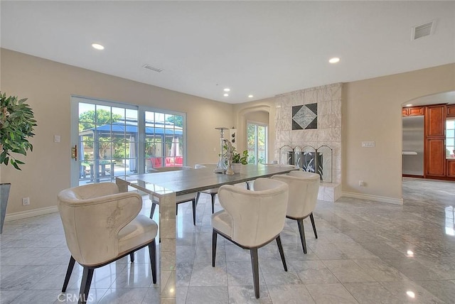 dining room with a healthy amount of sunlight, visible vents, and a tiled fireplace