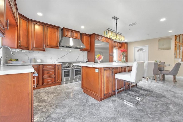 kitchen featuring visible vents, premium appliances, light countertops, under cabinet range hood, and a sink