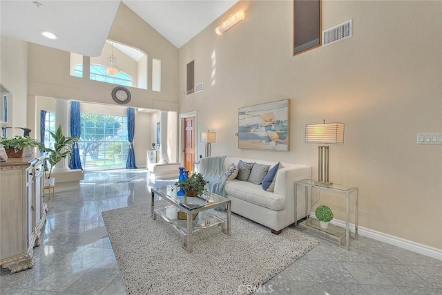 living room featuring marble finish floor, visible vents, a towering ceiling, and baseboards