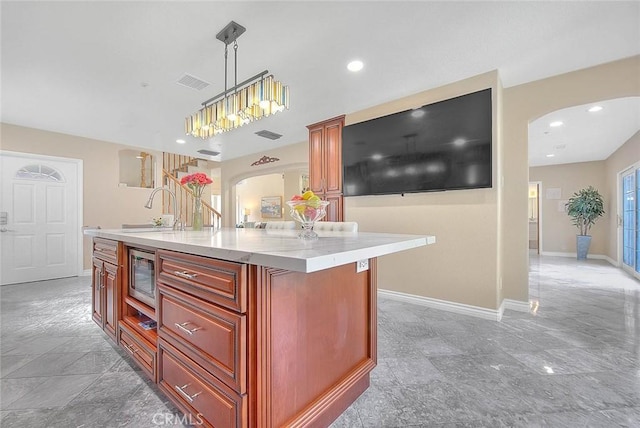 kitchen featuring arched walkways, a sink, visible vents, baseboards, and stainless steel microwave