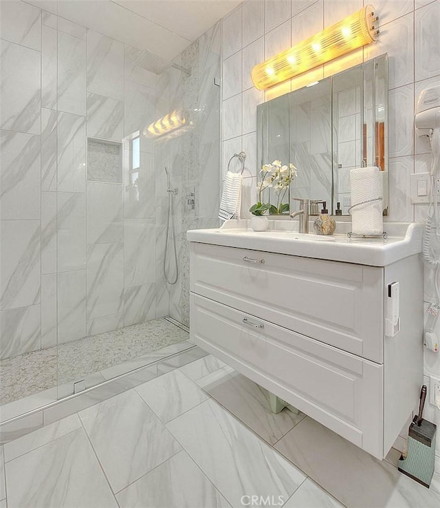 full bath with marble finish floor, a marble finish shower, vanity, and tile walls