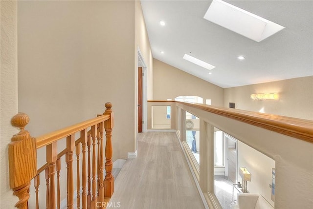 hall featuring light wood finished floors, lofted ceiling with skylight, an upstairs landing, and recessed lighting