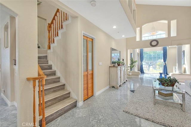 corridor with a towering ceiling, stairway, baseboards, and recessed lighting