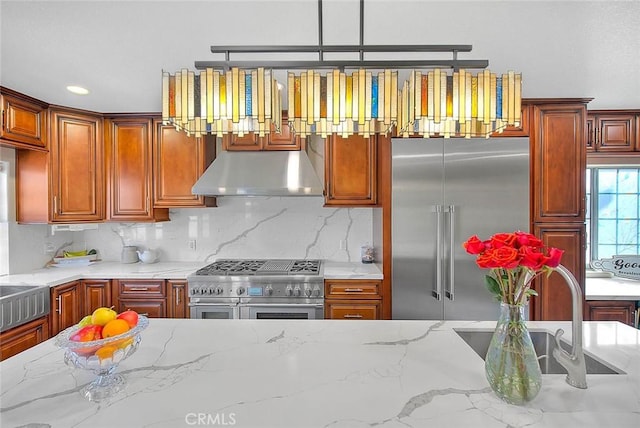 kitchen with under cabinet range hood, tasteful backsplash, high quality appliances, and light stone counters