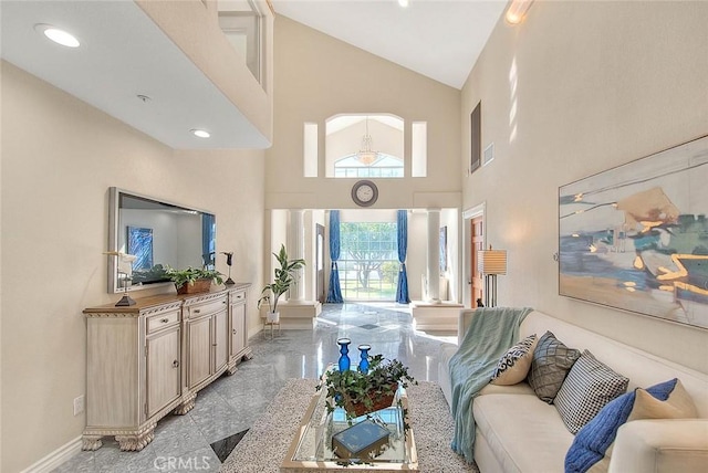 living area featuring high vaulted ceiling, marble finish floor, and baseboards