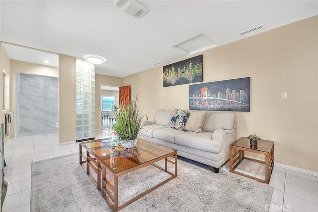 tiled living area featuring attic access, visible vents, and baseboards