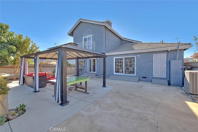 rear view of property with stucco siding, a gazebo, an outdoor hangout area, a patio area, and central AC