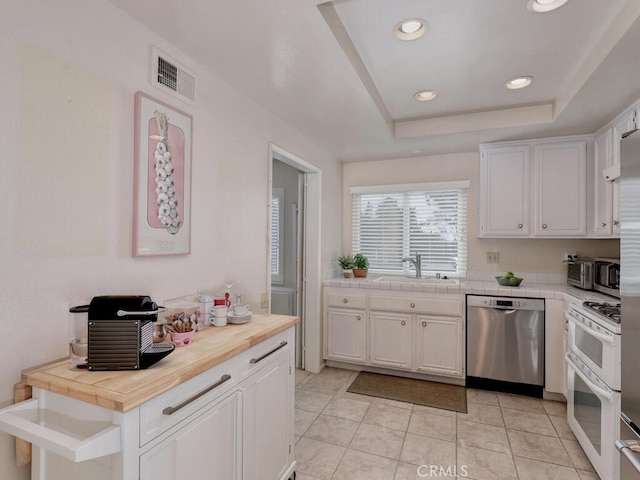 27740 Via Sarasate, Mission Viejo, CA 92692 - kitchen with stainless steel dishwasher, range with two ovens, white cabinets, tile counters, and recessed lighting