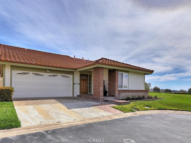 view of front of house featuring a front lawn, a tiled roof, an attached garage, and driveway