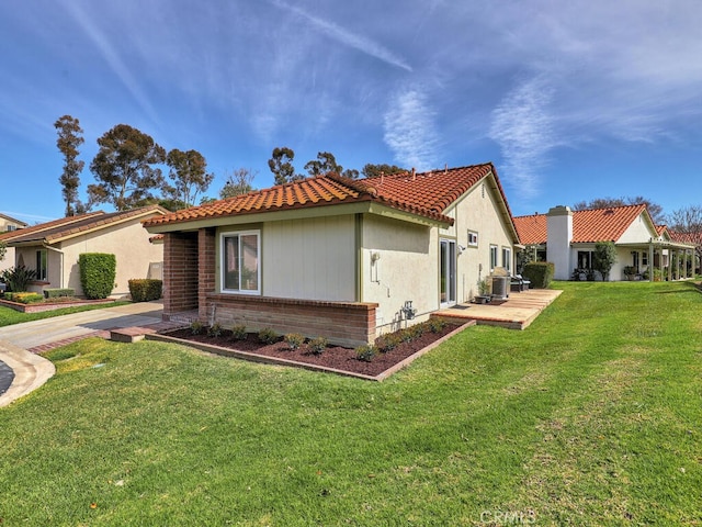 view of home's exterior with a lawn, a tile roof, central AC, and stucco siding