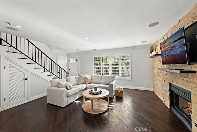 living room with dark wood-type flooring, a fireplace, a textured ceiling, and stairs