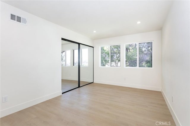 unfurnished bedroom with recessed lighting, visible vents, baseboards, a closet, and light wood finished floors