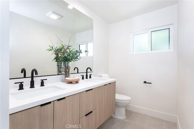 bathroom with double vanity, tile patterned flooring, a sink, and toilet