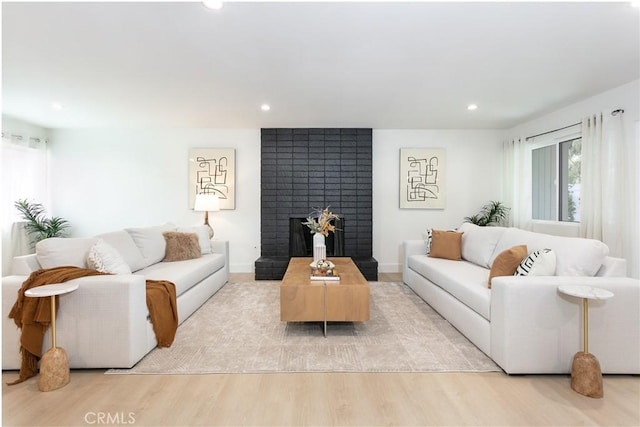 living area with recessed lighting, a fireplace, and light wood finished floors