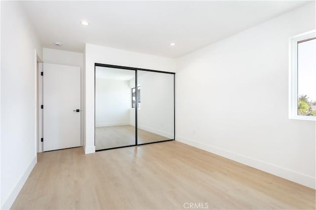 unfurnished bedroom with light wood finished floors, baseboards, a closet, and recessed lighting