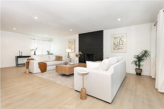 living room featuring recessed lighting, a brick fireplace, and light wood-style floors