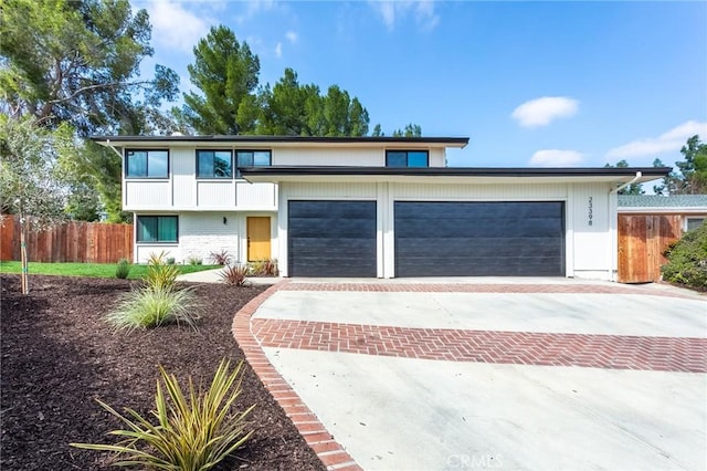 view of front of home with a garage, brick siding, decorative driveway, and fence