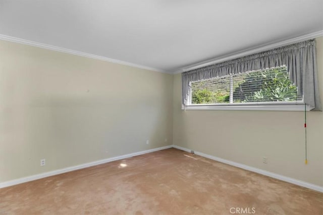 carpeted empty room featuring baseboards and crown molding