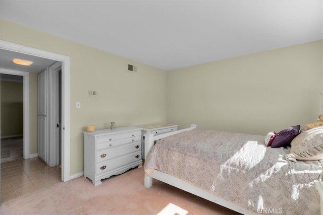 bedroom with light colored carpet, visible vents, baseboards, and light tile patterned flooring