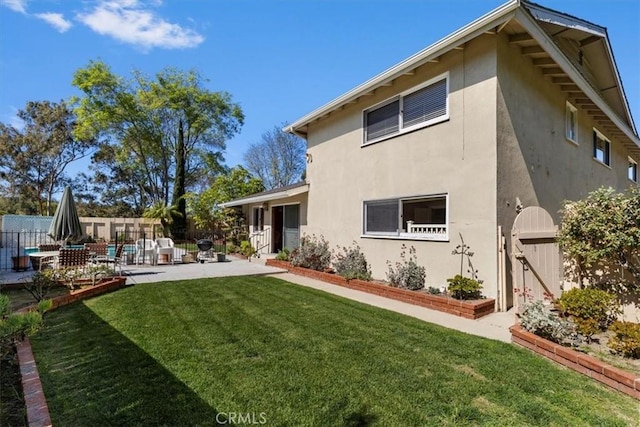 back of property with a lawn, a patio area, fence, and stucco siding