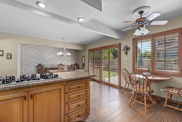 kitchen featuring light wood-style flooring, ceiling fan with notable chandelier, tasteful backsplash, beamed ceiling, and stainless steel gas stovetop