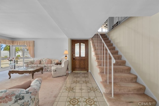 entryway with light tile patterned floors, stairs, and a wealth of natural light