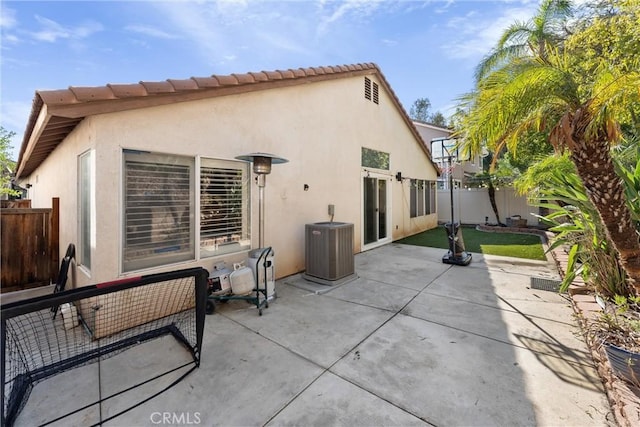 rear view of property featuring stucco siding, a patio, central AC, and fence