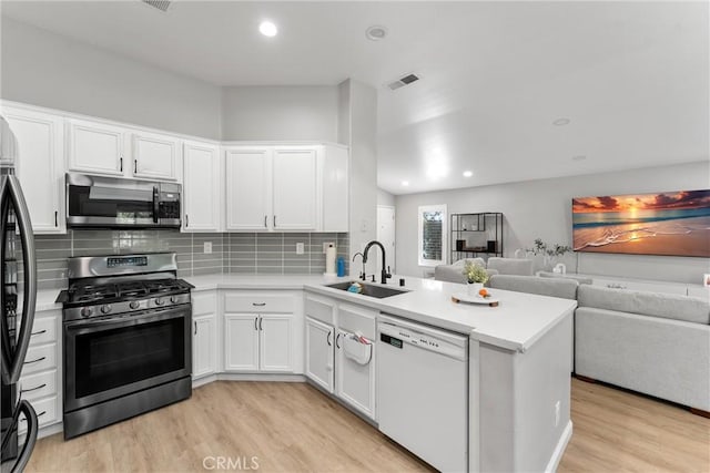 kitchen with visible vents, a sink, open floor plan, stainless steel appliances, and a peninsula