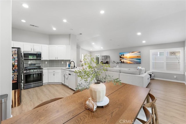 dining room featuring recessed lighting, baseboards, light wood-type flooring, and lofted ceiling