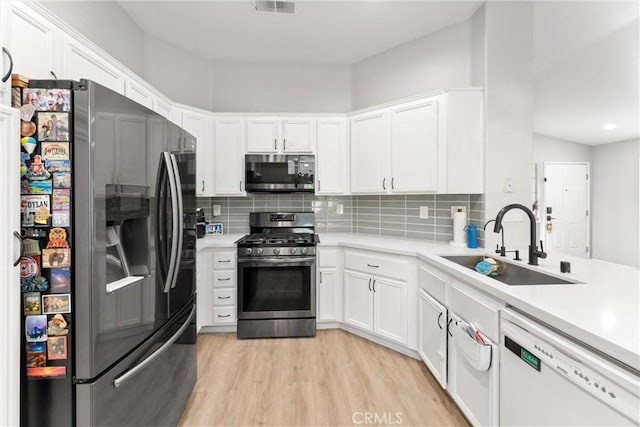 kitchen with a sink, light countertops, light wood-type flooring, and stainless steel appliances