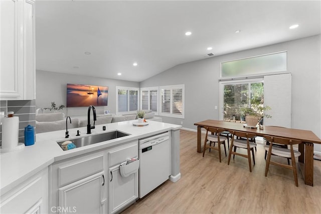 kitchen with light wood finished floors, dishwasher, light countertops, white cabinets, and a sink