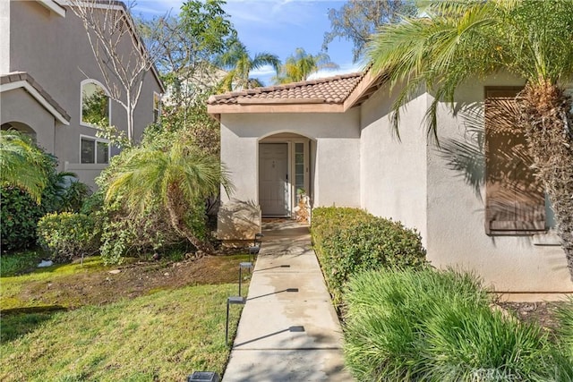 view of exterior entry featuring a tiled roof and stucco siding