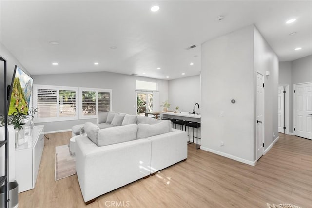 living room featuring lofted ceiling, recessed lighting, baseboards, and light wood finished floors