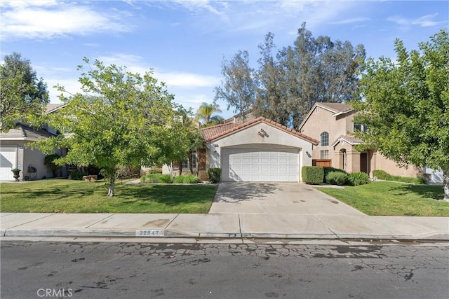 view of front facade with a tile roof, concrete driveway, a front yard, stucco siding, and an attached garage