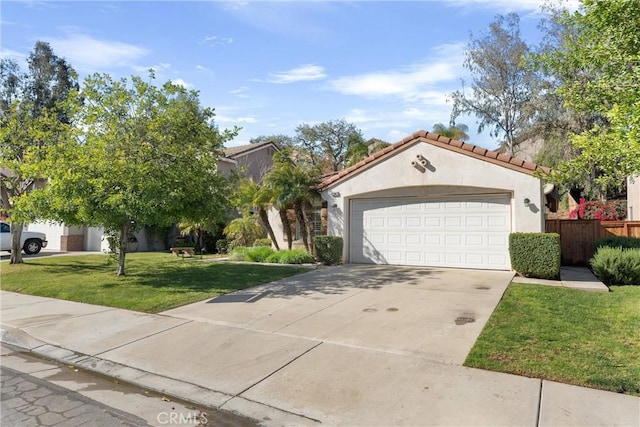 mediterranean / spanish house with stucco siding, concrete driveway, an attached garage, a front yard, and a tiled roof