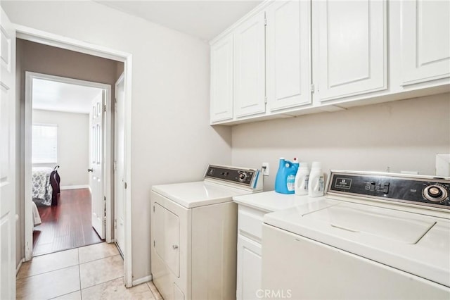 laundry area with washer and dryer, light tile patterned flooring, cabinet space, and baseboards