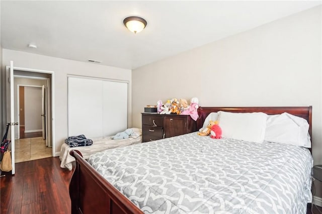 bedroom with dark wood-type flooring, a closet, and visible vents