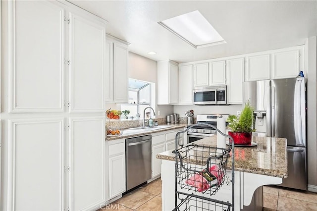 kitchen with stainless steel appliances, white cabinetry, a sink, and light tile patterned floors